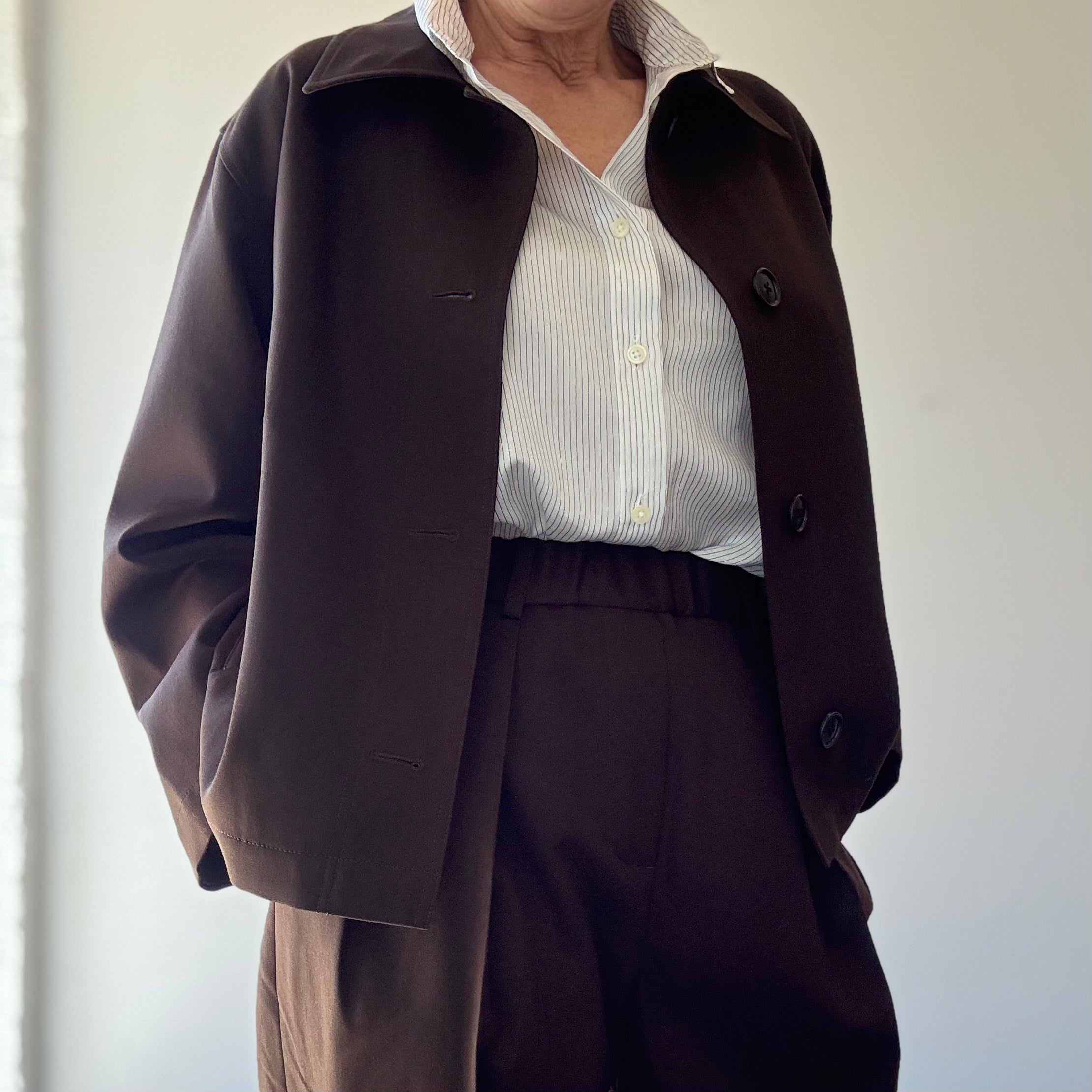 Model's torso on black background wearing Nicholson and Nicholson Toby-WO Trouser in brown, with brown jacket.