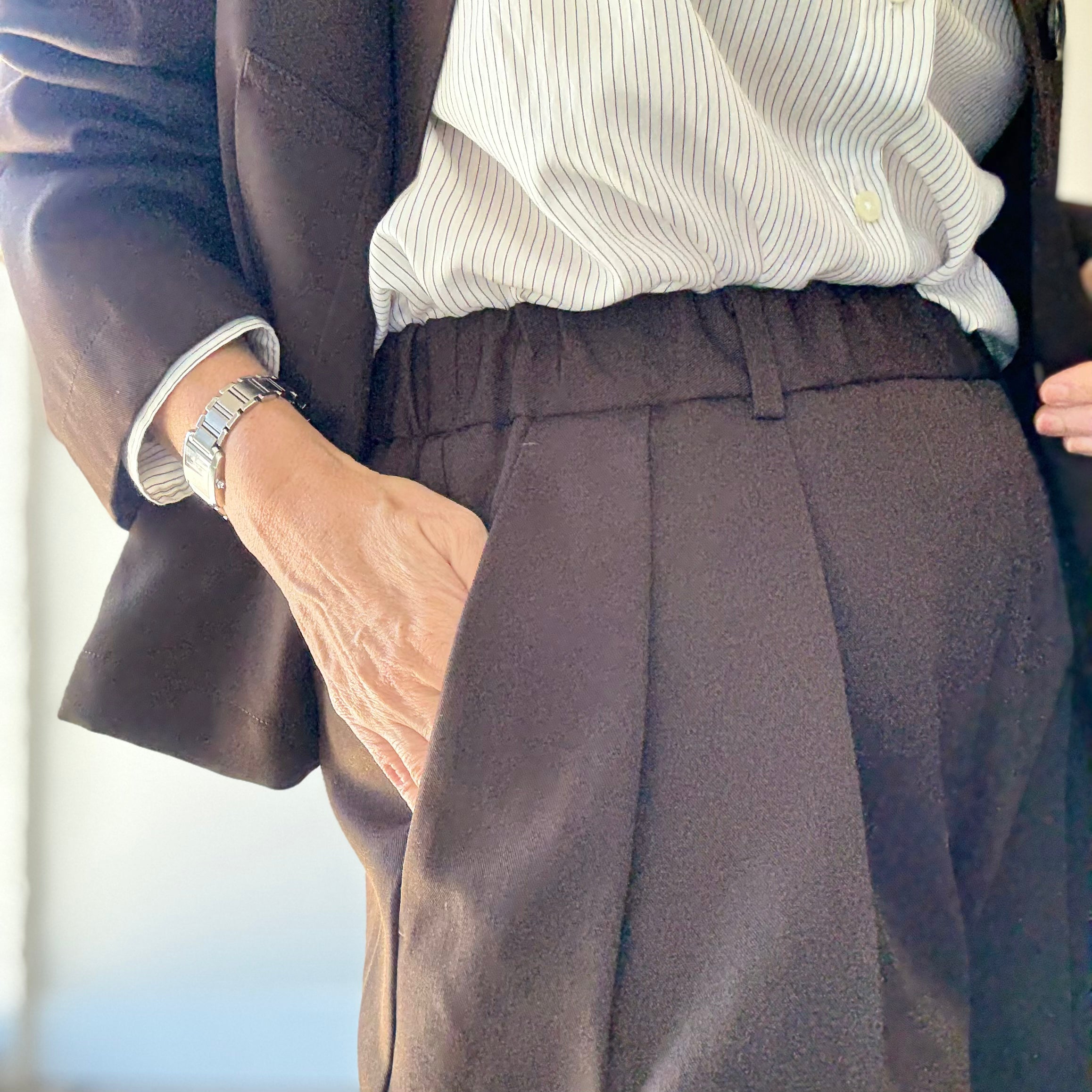 Close-up of elasticated waistband on Nicholson and Nicholson Toby-WO Trouser in brown, with model's hand in pocket.