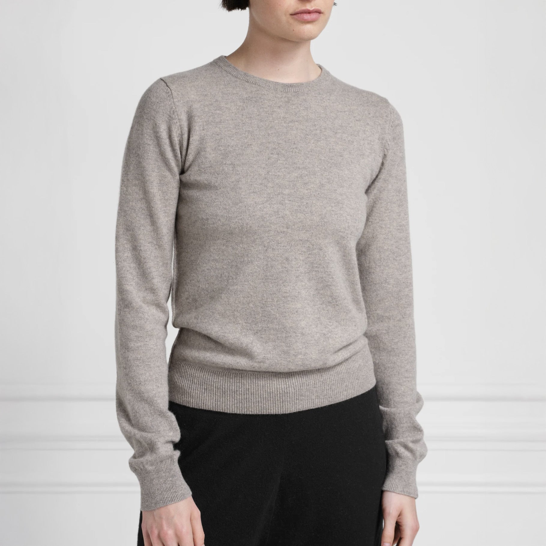 Model on grey wall wears Extreme Cashmere no. 41 Body Sweater in moss grey