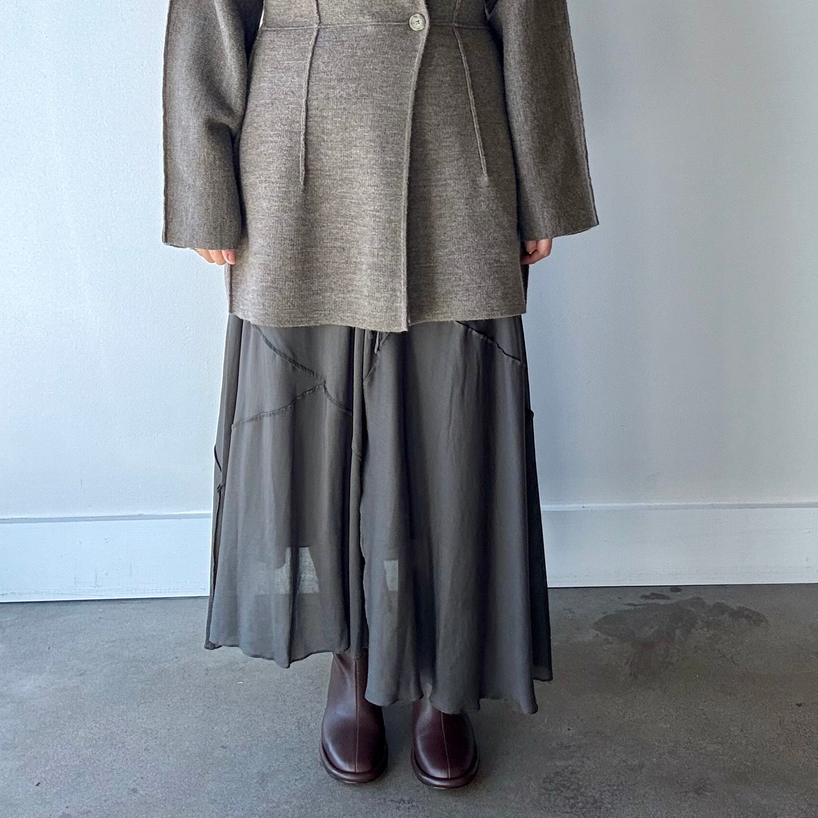 Model's torso and legs shown wearing dark grey Lauren Manoogian seamed skirt with grey knit blazer and brown boots.