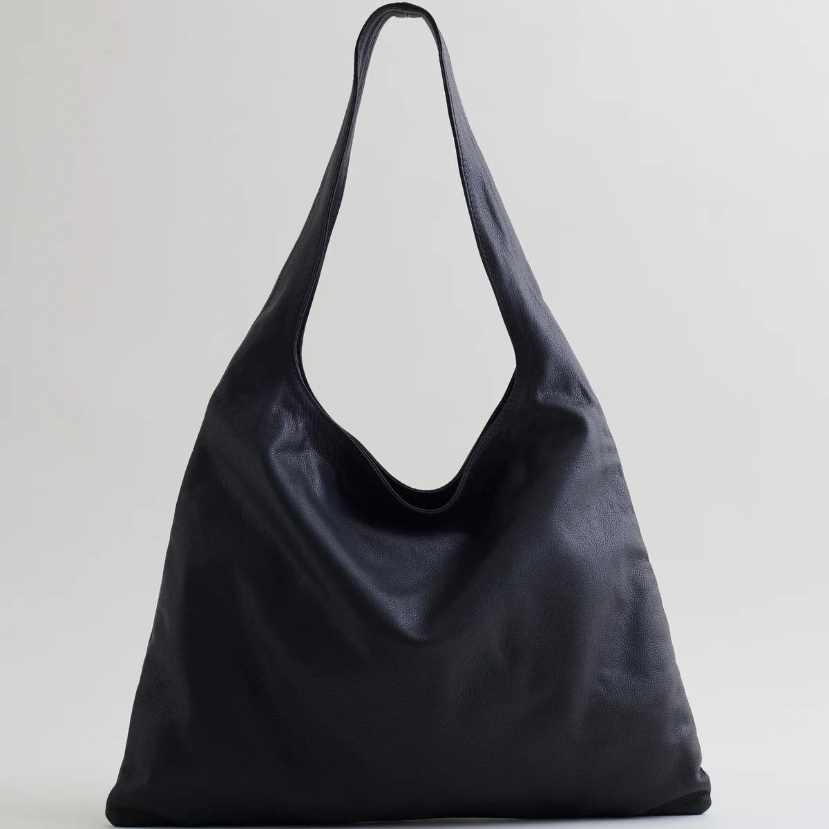 Are Studio Stella handbag. Black leather soft form shoulder bag on grey background.