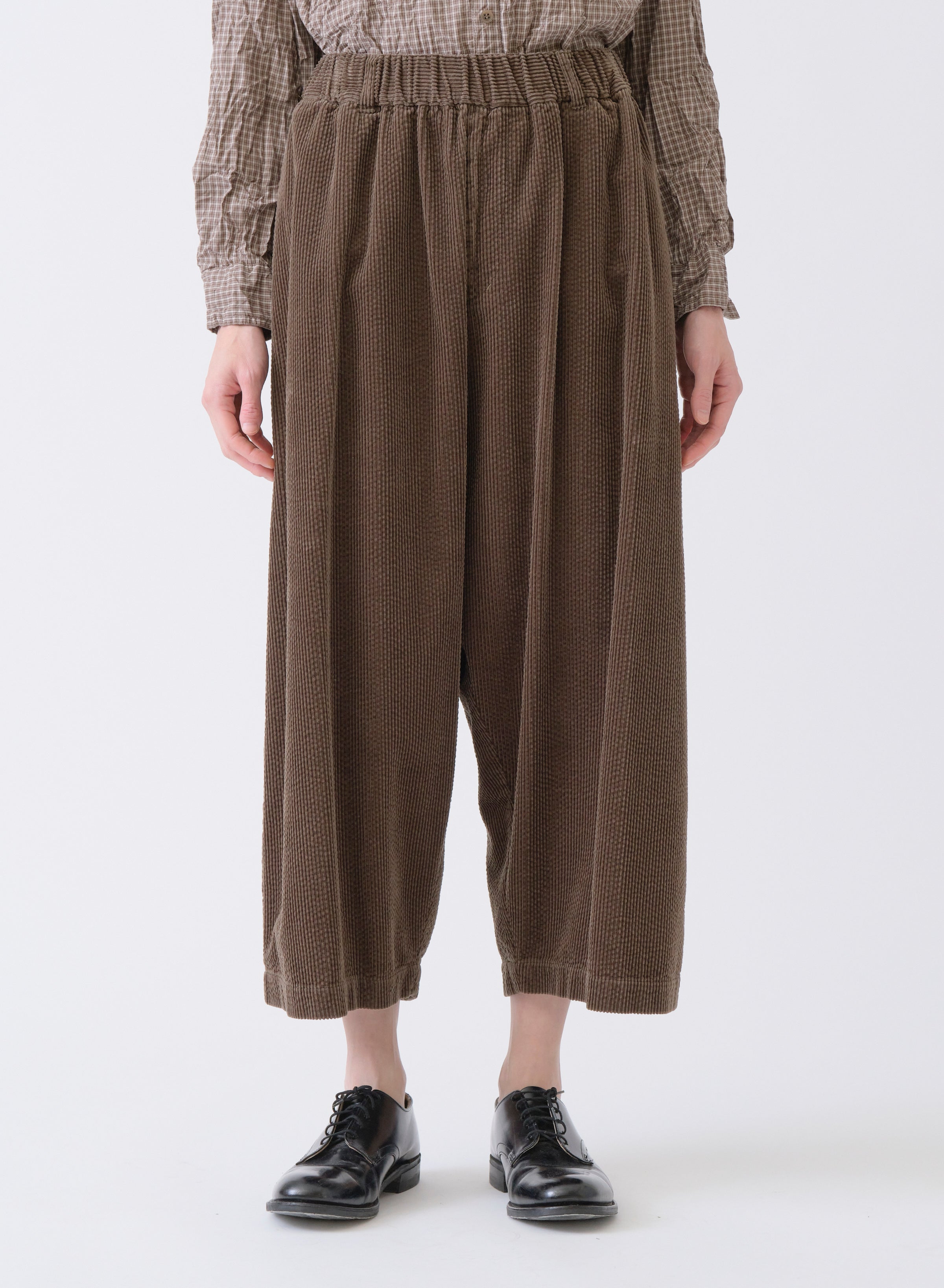Model on grey backdrop wears Pas de Calais brown Corduroy Sarrouel cropped Pants with black shoes