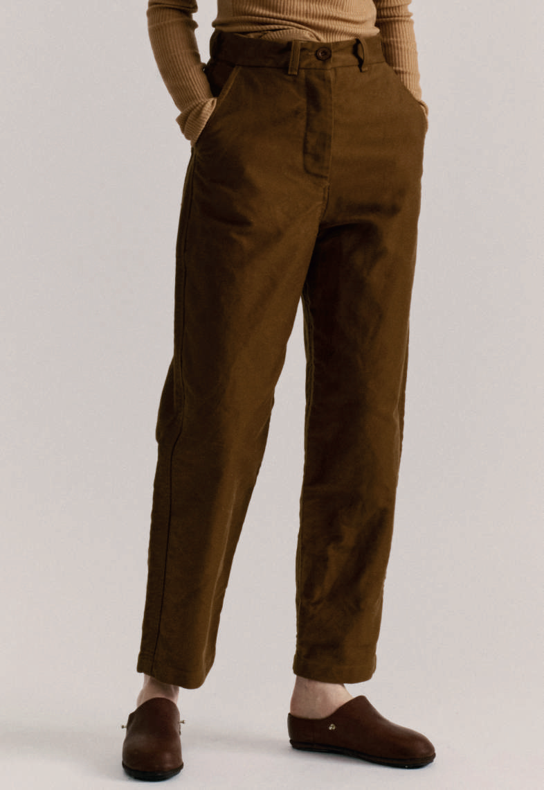 Model on grey backdrop from waist down wears Casey Casey brown cotton Ikla Pants with brown clogs
