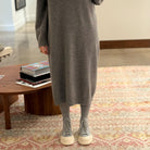 Front view of model standing on carpet wearing Sofie D'Hoore Fairway Leather Ankle Boots with grey knit dress