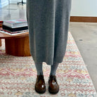 Close-up of model on carpet wearing grey knit dress and Sofie D'Hoore Falcone-LVATO shoes.