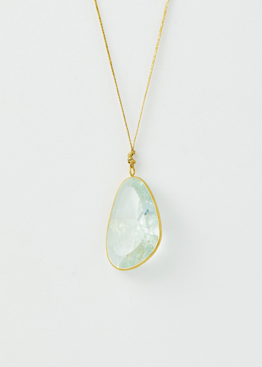 Close-up of Pippa Small Colette pendant necklace with delicate gold chain and abstract faceted aquamarine stone
