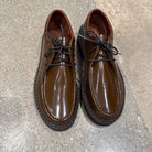 Pair of Sofie D'Hoore Falcone-LVATO shiny brown leather wallabee lace-up shoes on concrete floor, alt photo.