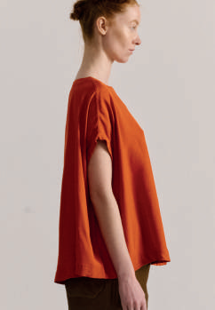 Alt side view of model on grey backdrop wearing Casey Casey Francesca sleeveless top in orange 
