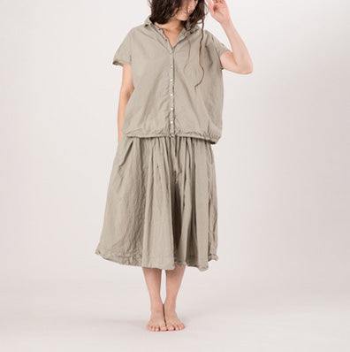 Model on grey backdrop wears ALBUM DI FAMIGLIA grey sleeveless cotton shirt with buttons and matching skirt