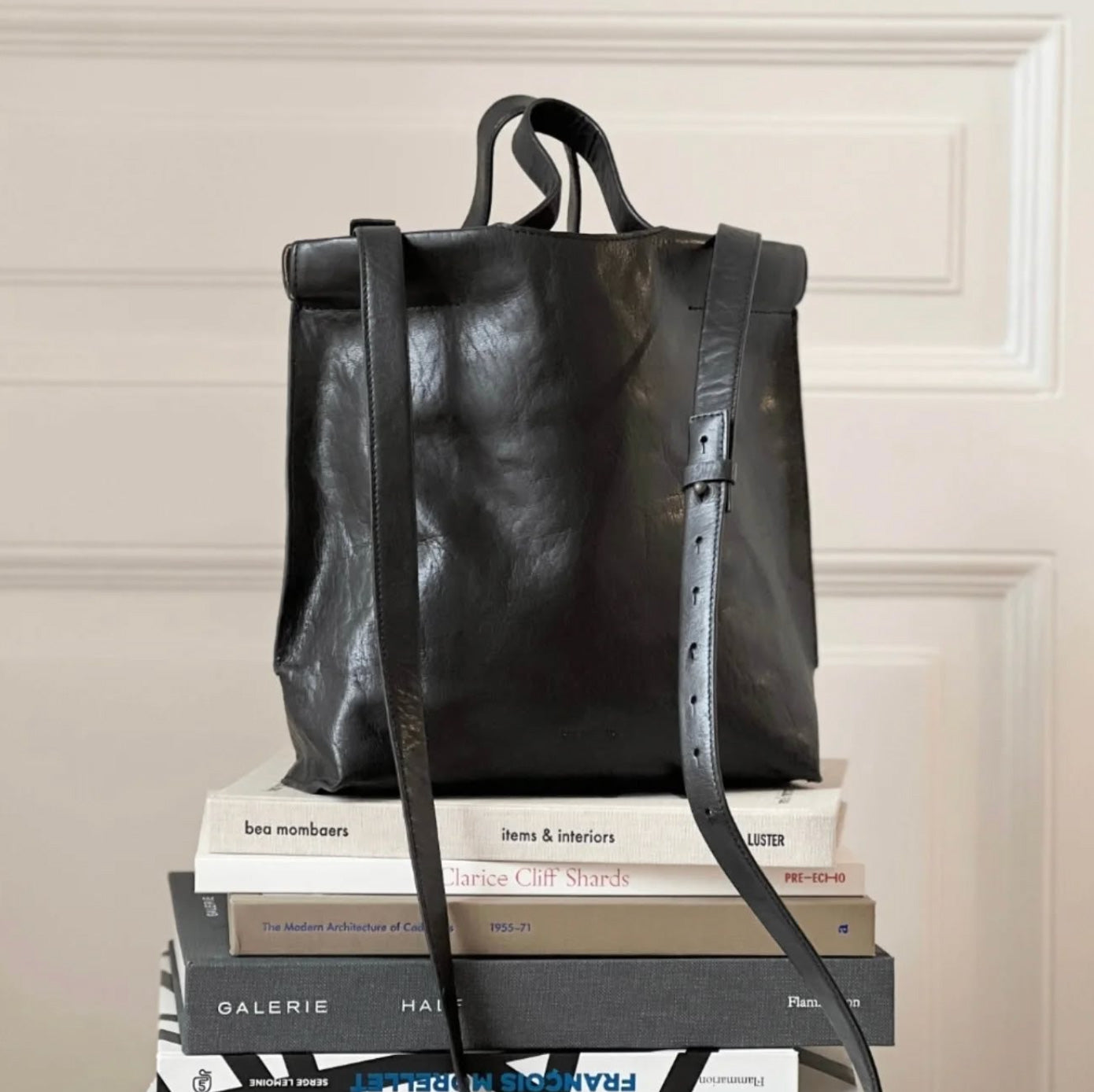 BEA MOMBAERS black leather bag displayed on pile of books