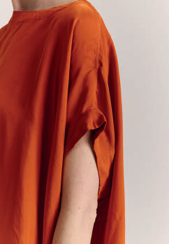 Close-up on draping of sleeve in Casey Casey Francesca sleeveless top in orange 