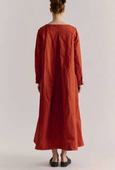 Back view of model on grey backdrop wearing Casey Casey dress in rust orange