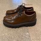 Side view of pair of Sofie D'Hoore Falcone-LVATO shiny brown leather wallabee lace-up shoes on concrete floor.