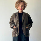 Model on grey backdrop wears PAS DE CALAIS brown cotton corduroy jacket with black shirt