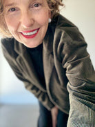 Model adjusts camera in PAS DE CALAIS brown cotton corduroy jacket with black shirt