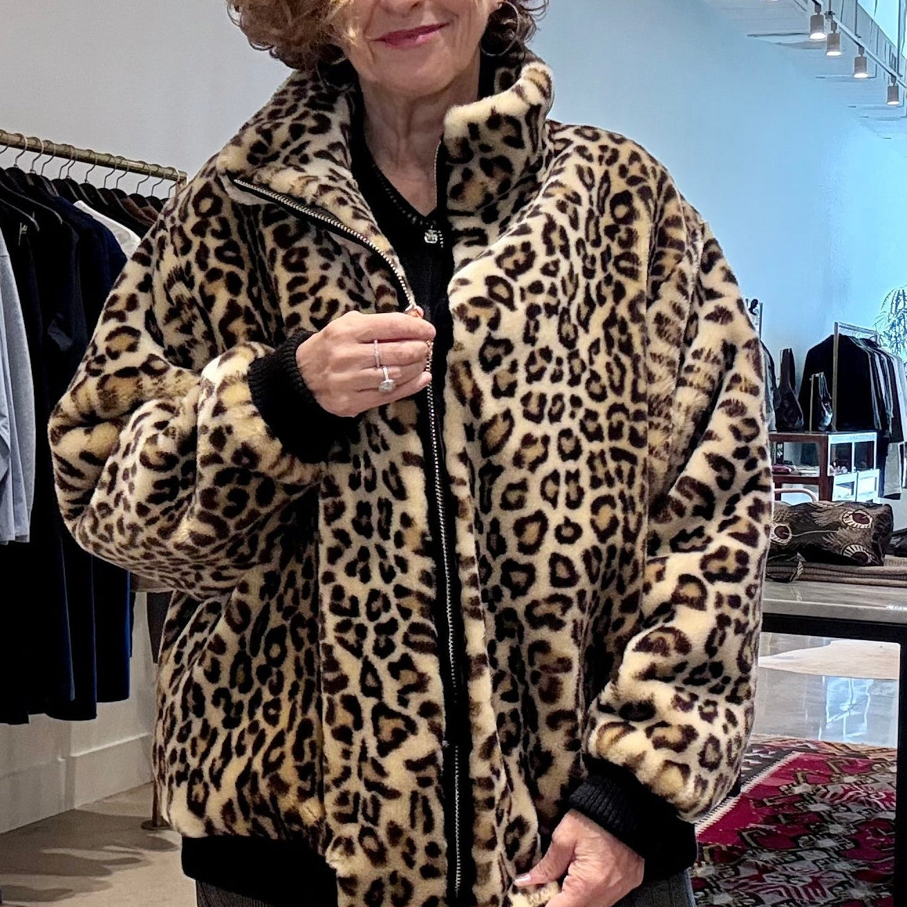 Model wears APOINT ETC faux fur, leopard-print Blouson Bomber jacket over black top, being zipped up