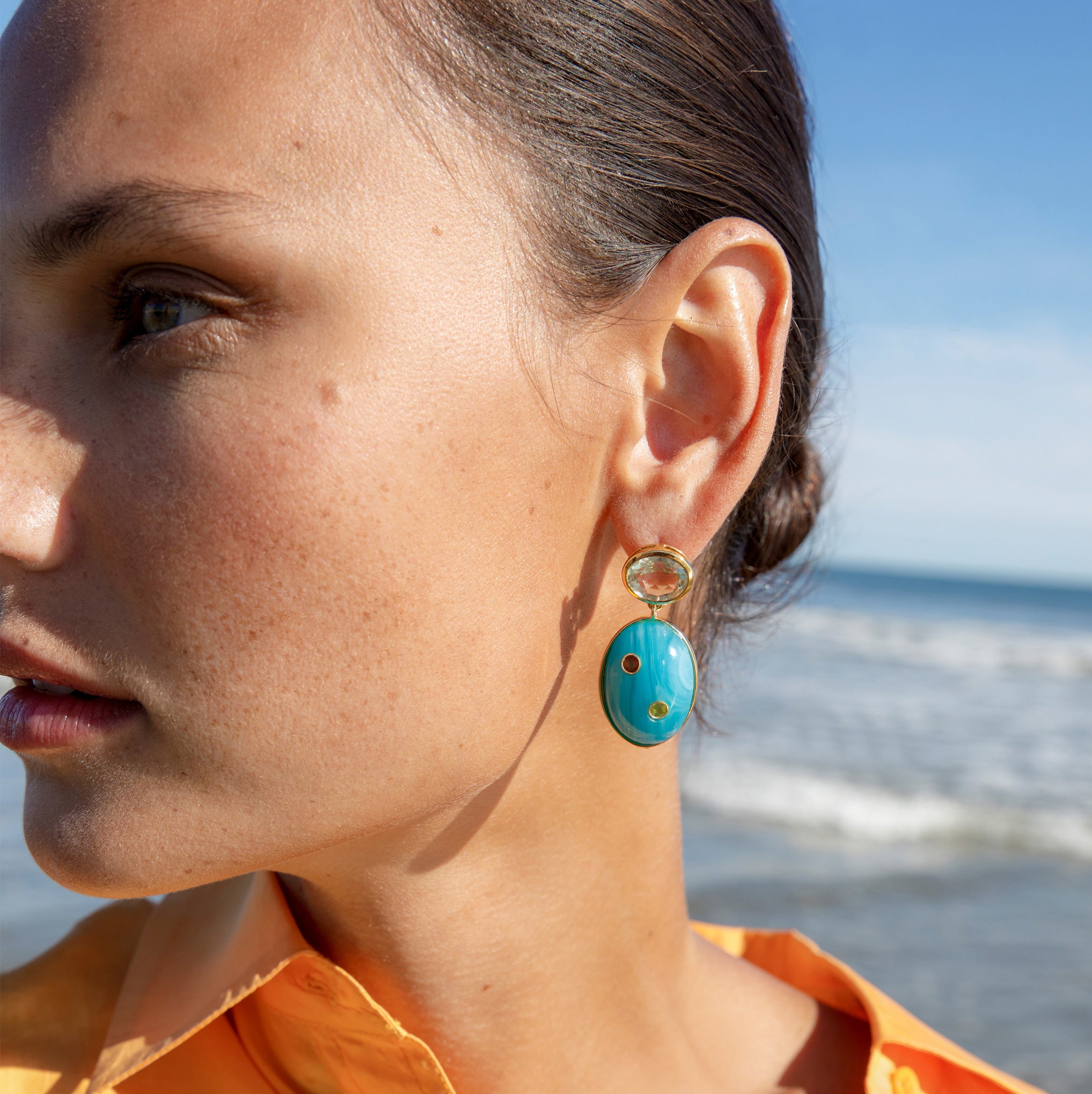 Close-up of model at the beach wearing the Blue Mountain Earrings.