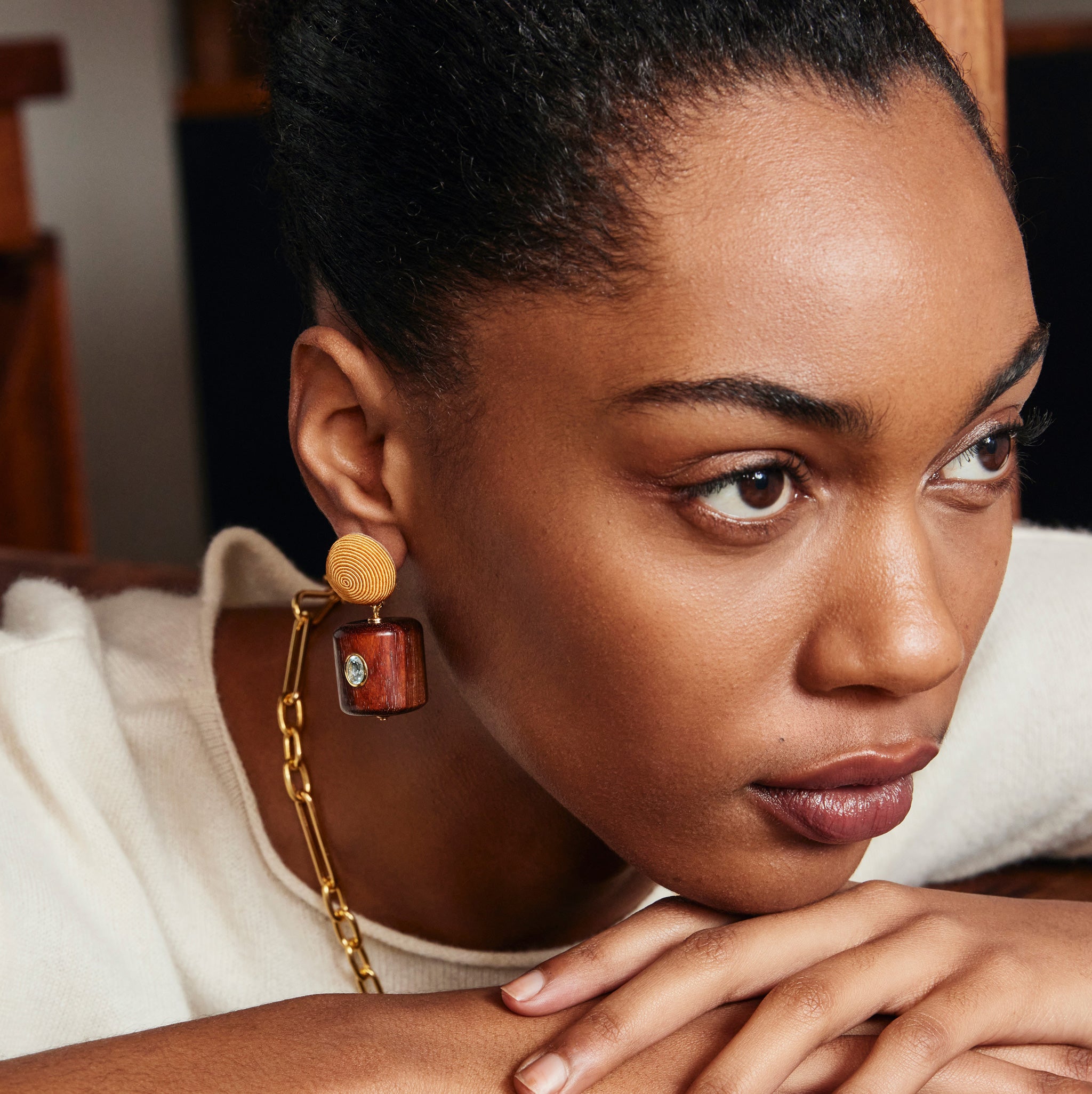Model poses with hands under chin and wears cream top with Lantern Earrings.