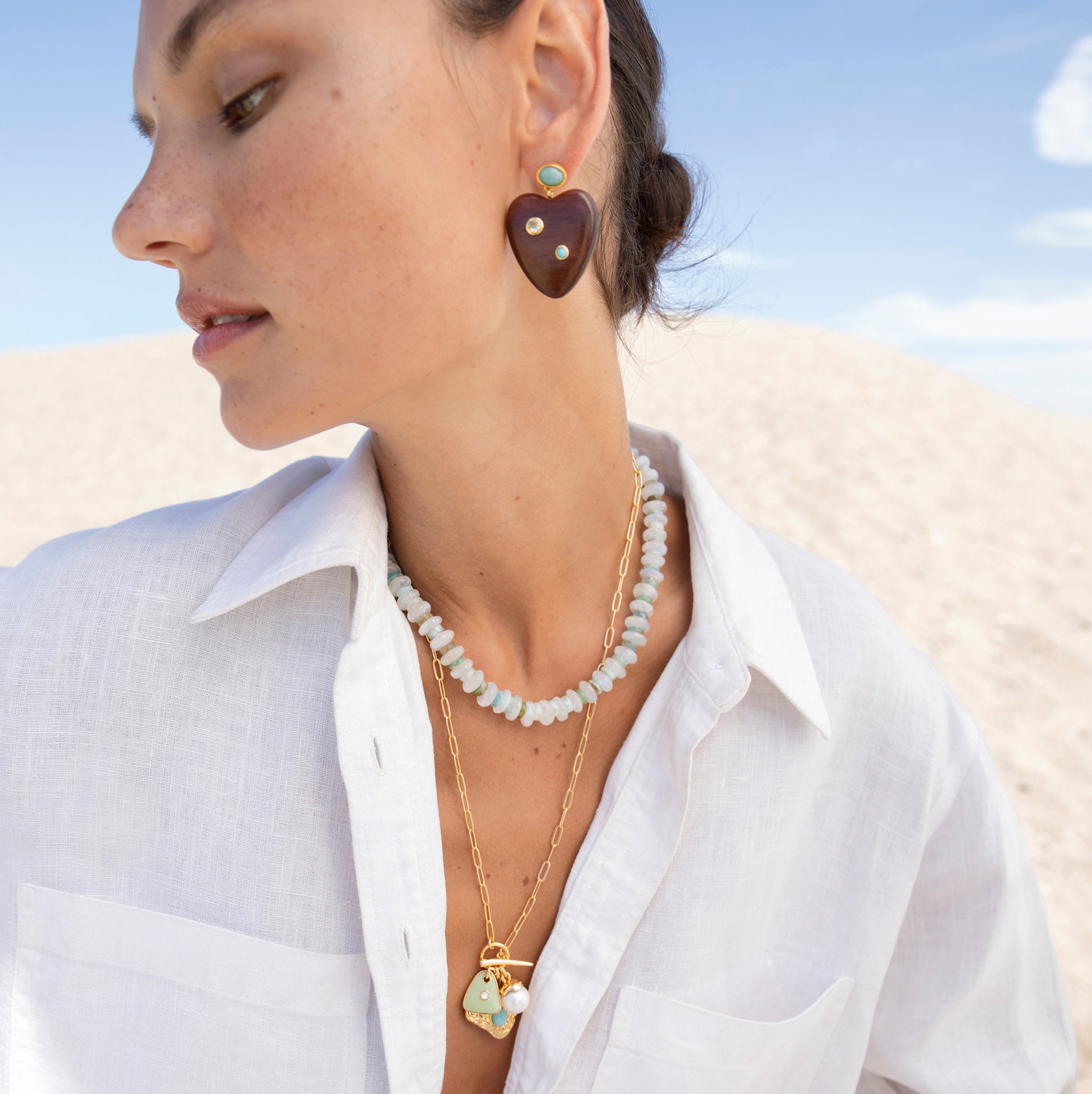 Model at the beach wearing the Lizzie Fortunato Tola Necklace with other statement jewelry