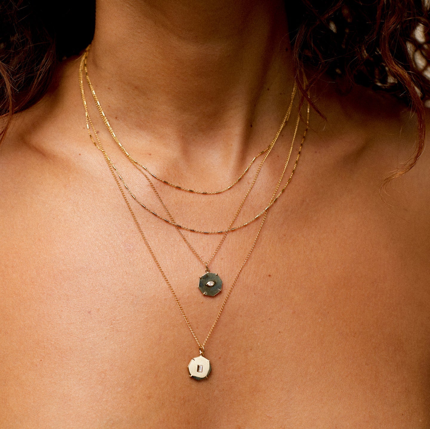 Close-up of model's neck in multiple gold chains and Zahava charms