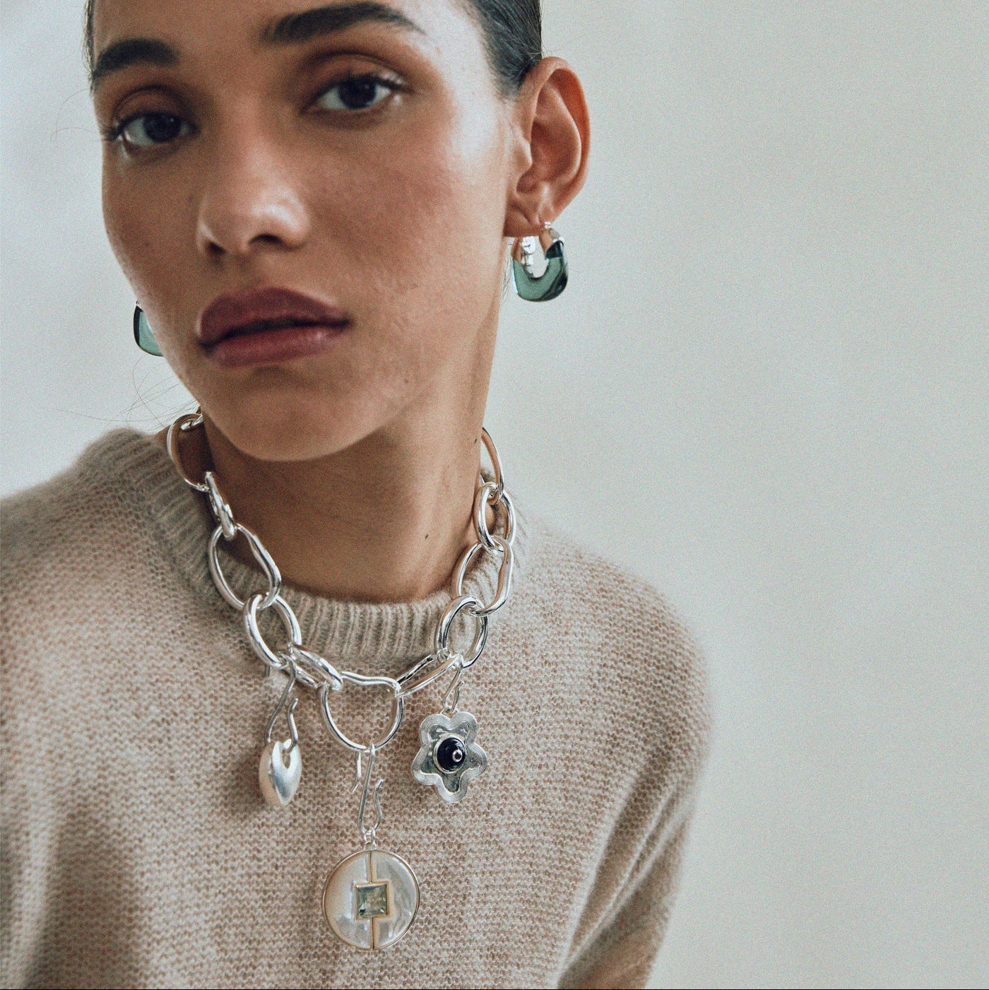 Model in grey sweater wears Porto Chain in Silver with hanging charms