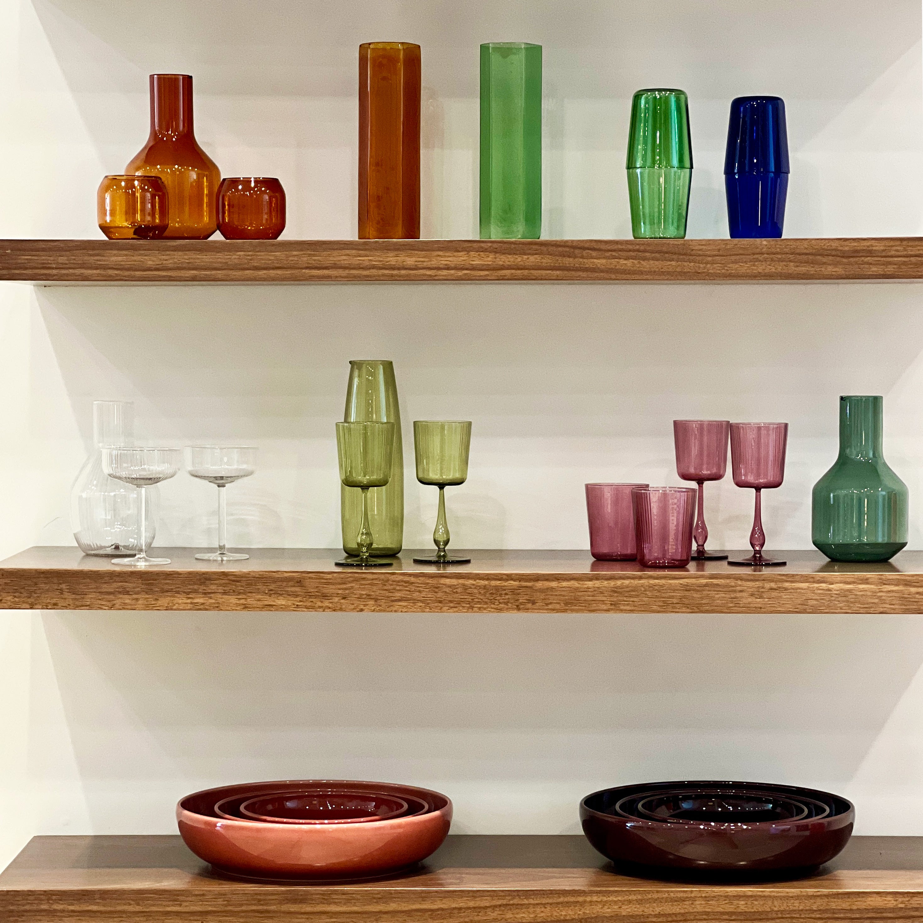 Wooden shelves with colorful glassware and bowls