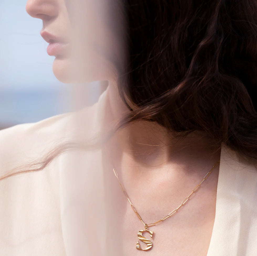 Close-up of model's neck wearing Zahava Sunbeam Large Letter Diamond "S" Charm on gold chain