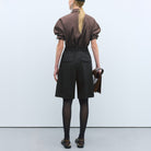 Model in Cordera black bermuda shorts, back view.