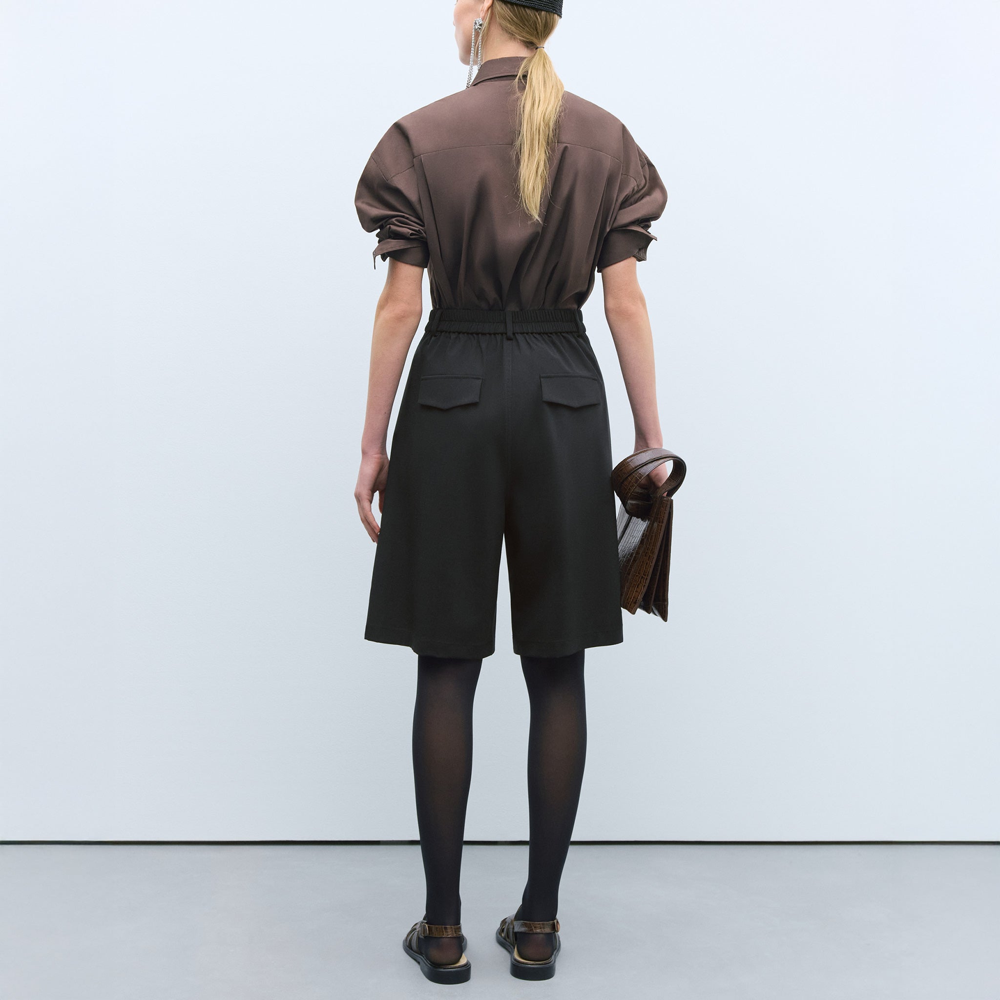 Model in Cordera black bermuda shorts, back view.