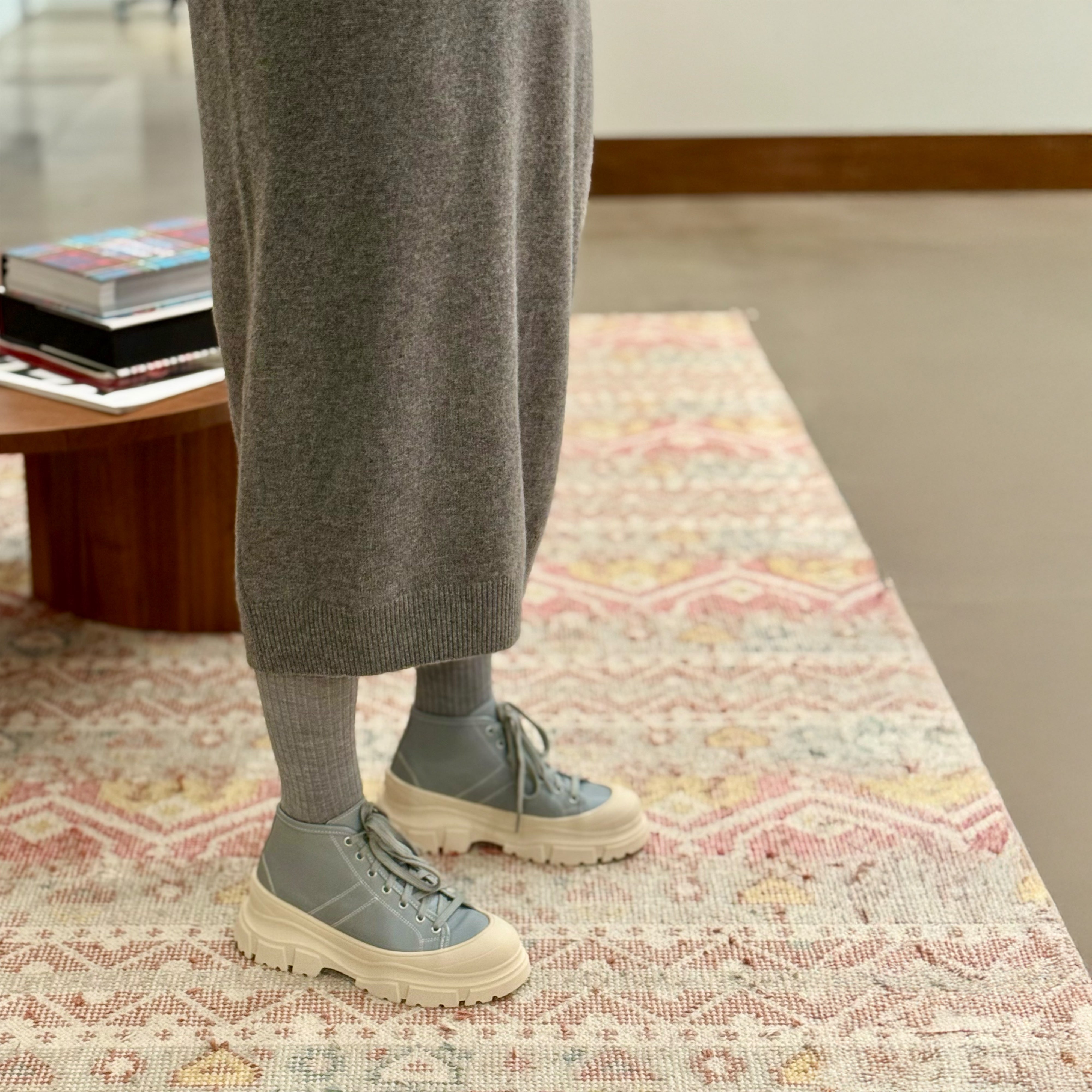 View of model's legs standing on carpet wearing Sofie D'Hoore Fairway Leather Ankle Boots in blue with white chunky soles