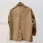 back of TOOGOOD cotton khaki mechanic jacket on hanger against white backdrop